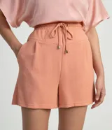 Short de poliéster color salmón con cintura elástica, cordón de ajuste, bolsillos laterales y pliegues frontales.
