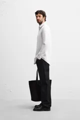 Camisa celeste de corte slim fit, confeccionada en tejido de algodón. Tiene cuello italiano, mangas largas con puños abotonados y cierre frontal con botones.
