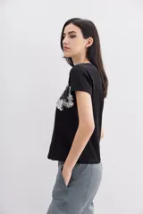 Remera negra de algodón con calce relajado, cuello redondo y mangas cortas. Presenta bordados florales con lentejuelas en el frente.