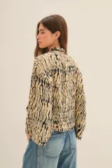 Kimono de manga ancha, estilo japonés, con estampado que imita piel de cebra en tonos beige y negro. El borde está decorado con apliques de mostacillas y bordados florales en tonos rojizos, verdes y dorados.