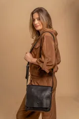 Bandolera de hombro color gris claro, con solapa frontal y correa ajustable. Presenta un diseño simple y práctico, ideal para uso diario.