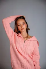 Buzo de punto color rosado, con cuello polo y cierre frontal parcial, de manga larga y diseño holgado.