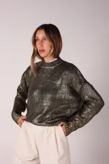 Buzo negro con lentejuelas doradas, cuello alto y mangas largas.