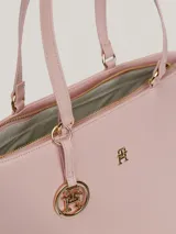Bolso tipo tote color rosa pálido, con doble asa de hombro y cierre superior con cremallera. Incluye un dije colgante con el logo de la marca y el logo metálico en la parte frontal.