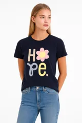 Remera azul marino con estampado de la palabra "Hope" en letras de diferentes colores y una flor amarilla.
