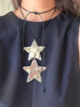 Collar con dos dijes grandes en forma de estrella plateada con textura, colgando de un cordón negro ajustable.