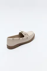 Zapato náutico color beige, de símil cuero, con cordones y suela marrón antideslizante.