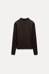 Camiseta blanca de manga larga con cuello alto y corte ajustado.