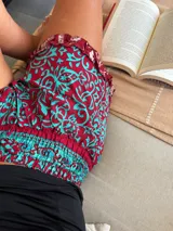 Short de seda con elástico fruncido en la cintura y volado en el ruedo. Presenta un estampado vibrante en tonos rojo/bordó y turquesa con motivos florales o arabescos.