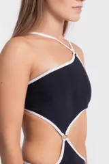 Traje de baño enterizo negro con contorno blanco, corte asimétrico y aberturas en la zona abdominal.