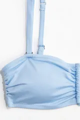 Top de bikini celeste strapless con breteles ajustables extraíbles, copas con relleno extraíble, alambre en V en el busto, reborde de silicona oculto en el escote y cierre de gancho ajustable en la espalda.