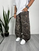 Pantalón baggy con estampado de camuflaje de hojas en tonos marrones y beige.
