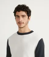 Suéter de punto blanco con cuello y mangas largas en color negro.