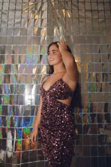 Vestido plateado con corte bajo el busto, abertura en la cintura y espalda descubierta. Se ata al cuello con dos tiras finas.