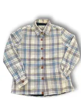 Camisa leñadora de franela a cuadros blancos, verdes, rojos y azules, con cuello clásico, cierre con botones de madera y corte recto.
