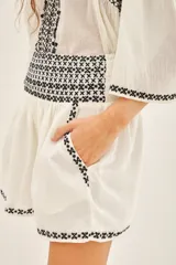 Minifalda blanca de algodón con bordados geométricos negros en el ruedo y cintura.