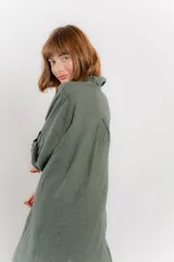 Vestido camisero midi color verde militar, de lino 100%, con silueta oversize, cuello camisero, mangas 3/4 con botón para ajustar y aberturas laterales.