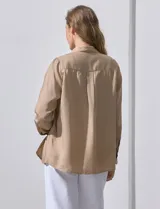 Camisa blanca de lyocell, marca Dash. Tiene cuello con solapa, abertura central con botones, mangas largas regulables con presilla y botón, y dos bolsillos delanteros aplicados.