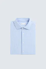 Camisa celeste a rayas verticales blancas, de corte recto, con cuello italiano abierto, mangas largas con puños abotonados y cierre frontal con botones.