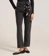 Pantalón mom de jeans con lavado oscuro, con trabillas en la cintura y pañuelo estampado de lunares atado como cinturón.
