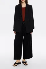 Pantalón negro de viscosa con corte campana, largo hasta los tobillos, cierre frontal de cremallera y corchete oculto, bolsillos diagonales delanteros y con vivo en la parte trasera, y cintura ajustable con cinturón textil.