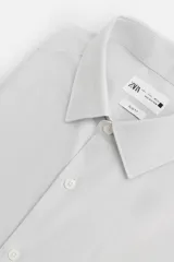 Camisa celeste de corte slim fit, confeccionada en tejido de algodón. Tiene cuello italiano, mangas largas con puños abotonados y cierre frontal con botones.