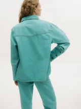 Campera de denim gastado color celeste, con cuello camisero, corte holgado y canesú con costuras delante y atrás.