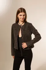 Campera de jean azul con apliques de strass plateados, corte clásico, con cuello redondo, bolsillos frontales y cierre con botones metálicos.