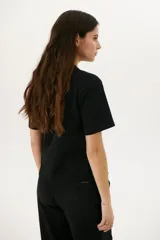Remera blanca de algodón de corte recto, con cuello redondo y mangas cortas. Presenta detalle de aberturas laterales con ojales metálicos.