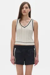 Top tejido de punto color crema con cuello en V y ribetes negros.