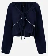 Blusa de mangas largas color azul marino, confeccionada en viscolino con 30% de lino, con escote V, lazo en el cuello con punta y bieses contrastantes luego abajo del escote, además del bajo de volado.