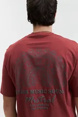 Remera color crema de manga corta con estampado en la espalda con diseño de plumas de pavo real y texto "Stars Music Sound Mistral Los Angeles California".