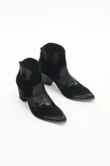 Botín negro de gamuza con apliques de cuero texturizado y remaches. Tiene cierre en el talón y taco cuadrado.
