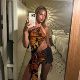 Minivestido con estampado de mariposas en tonos naranja y negro, con escote halter asimétrico y abertura en la cintura.