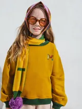 Bufanda azul y marrón con pompones grises, confeccionada en algodón.