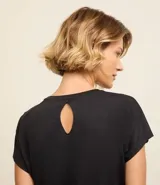 Remera deportiva negra de manga corta confeccionada en microfibra de poliamida ligera con agujeritos en los hombros y bieses en contraste color naranja en las sisas.