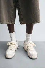 Zapatillas bajas de estilo skate color blanco y gris claro, con cordones y suela gruesa.