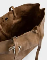 Cartera shopper negra de cuerina con manijas superiores y acceso mediante broche imantado. Incluye charm de perlas en forma de moño.
