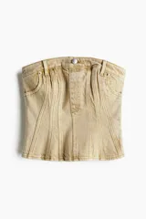 Bustier color beige confeccionado en denim rígido, con corte entallado, costuras decorativas verticales y bolsillos frontales.