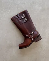 Bota de cuero color marrón con caña alta, hebillas y arnés.