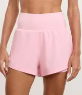 Bermuda deportiva femenina de microfibra color amarillo claro, con diseño de doble capa: un short interno ajustado y una capa externa suelta con bajo redondeado. Posee cintura alta.