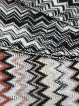 Bufanda larga Missoni con patrón de zigzag en tonos blanco, negro, marrón y naranja, y flecos en los extremos.