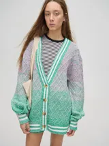 Cardigan tejido de punto con patrón de rombos en degradé de grises y blanco. Tiene corte oversize, mangas largas y cierre frontal con botones.