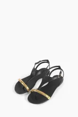 Sandalias planas negras con tira delantera y pulsera al tobillo, detalle de aplique metálico dorado en la puntera.