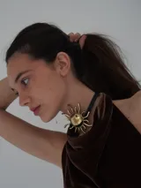 Collar de cuero negro con dije grande de bronce en forma de sol.