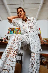 Pantalón blanco de tela calada con diseño de círculos, corte evasé y cintura elastizada.