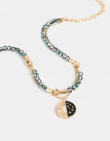 Collar corto doble con cadena dorada y cadena de mostacillas facetadas azules y grises con detalles dorados. Dije redondo con diseño de sol y estrellas.