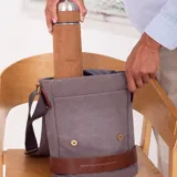 Morral gris de tela canvas con detalles en cuero marrón. Tiene correa larga regulable, tapa con broches magnéticos, bolsillo tipo guantera bajo la tapa, división interna con velcro y bolsillo trasero con broche magnético.