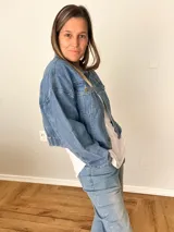 Campera de jean celeste con corte corto y fit relajado, botones metálicos frontales, bolsillos con solapa y espalda con elástico fruncido.