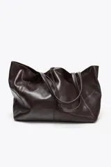 Bolso maxi shopper de cuero color marrón oscuro, con pespuntes a tono y asas de hombro. Incluye cierre con tiras y botón, y cartera con bolsillo extraíble.